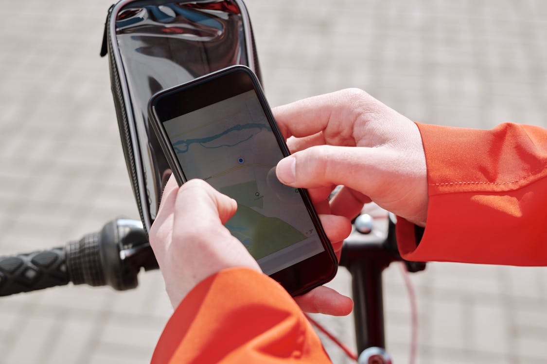 Close-up of a cyclist using a smartphone map for GPS directions in countries without street addresses.