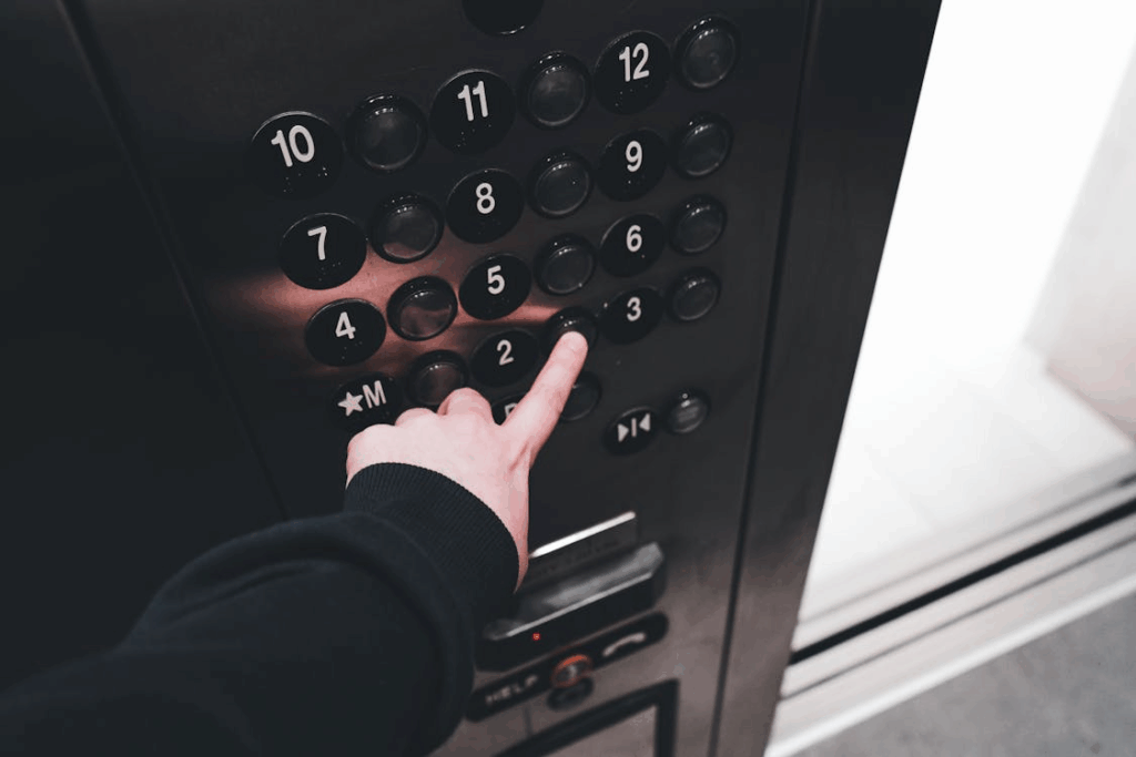 Hand presses on an elevator panel, highlighting numbered buttons and the absence of 13.