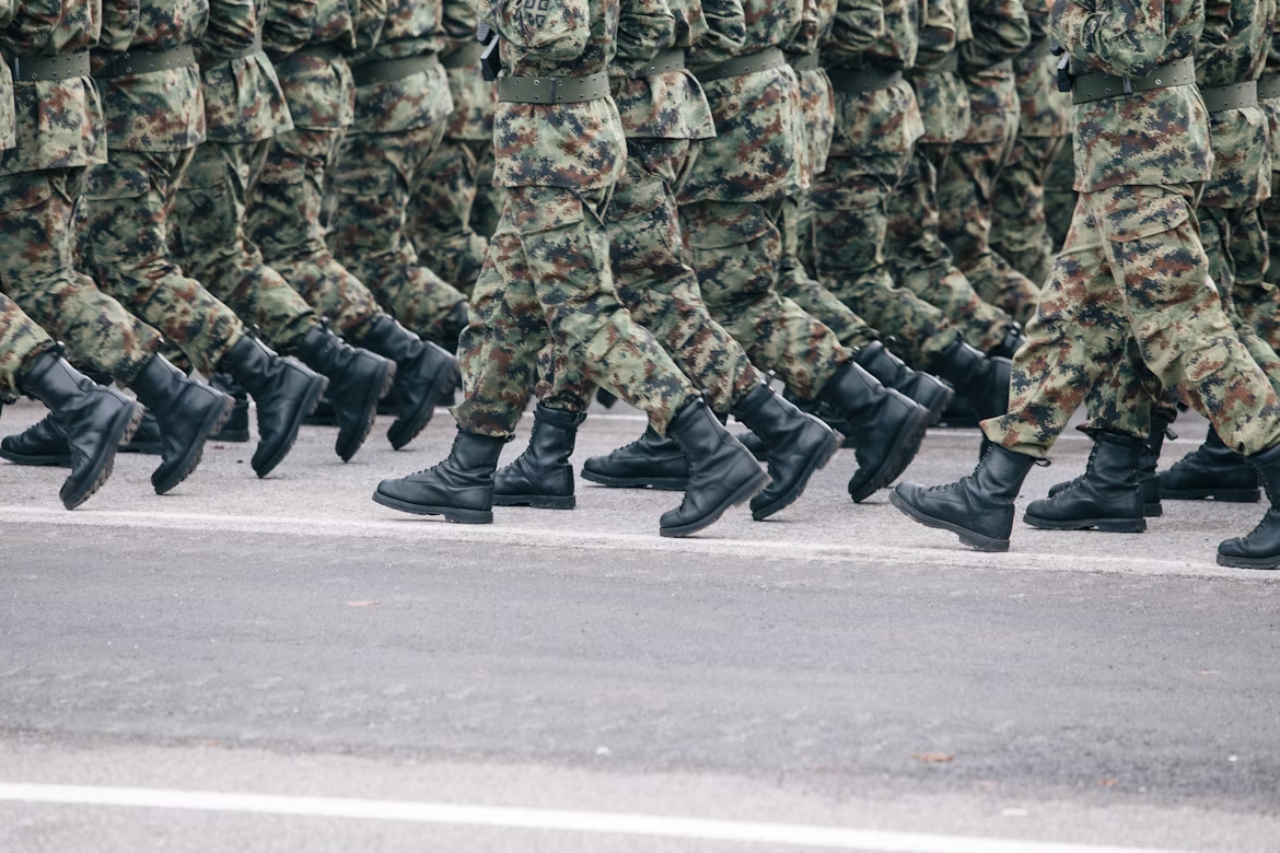Close-up of soldiers’ boots and camouflage uniforms marching in formation