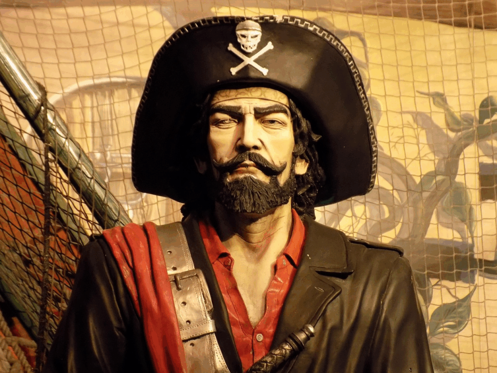 Statue of a classic pirate in a skull-and-crossbones hat, evoking Blackbeard and the real pirates behind Hollywood legends.