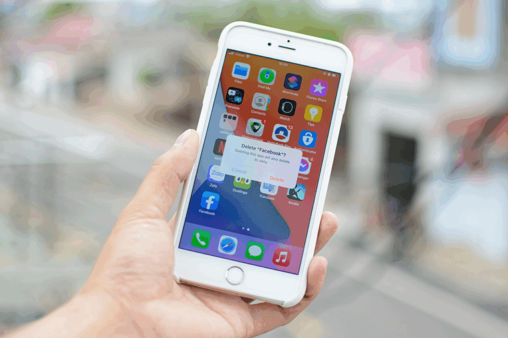 Hand holding an iPhone showing a “Delete Facebook?”, illustrating digital legacy planning.