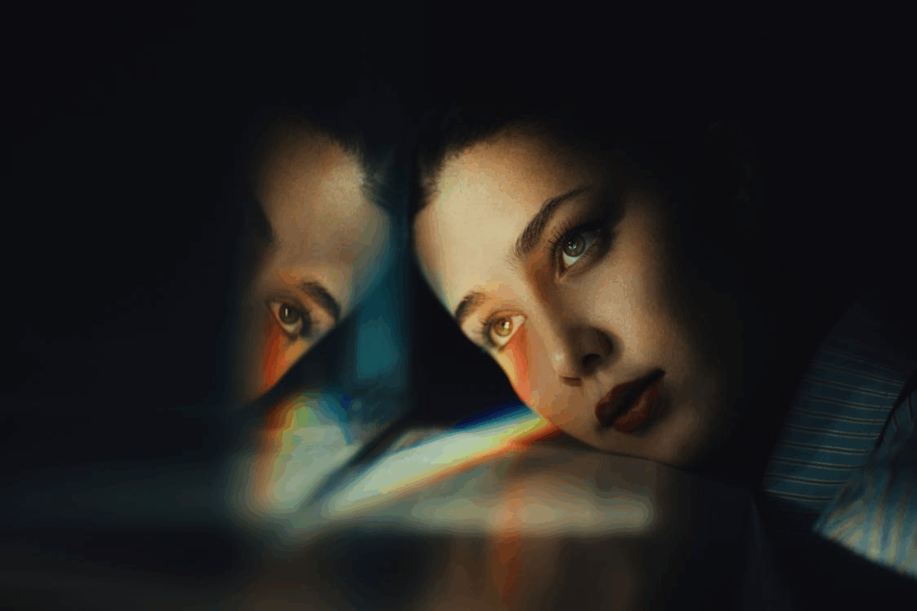 Woman gazing at her reflection with soft prism light, symbolizing inner monologue.